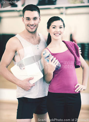 Image of two smiling people with scale in the gym