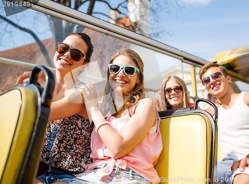 Image of group of smiling friends traveling by tour bus