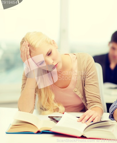 Image of tired teenage student with tablet pc and books