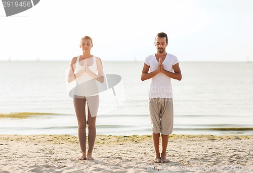 Image of smiling couple making yoga exercises outdoors