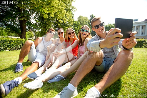 Image of smiling friends with tablet pc computer in park