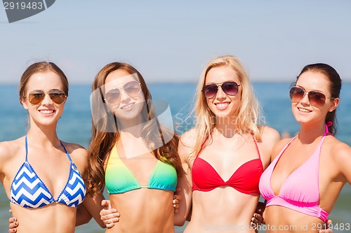 Image of group of smiling young women on beach