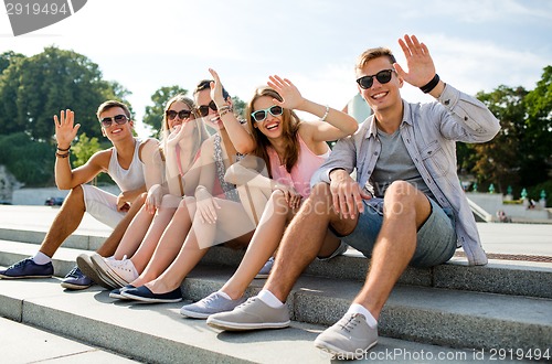 Image of group of smiling friends sitting on city street