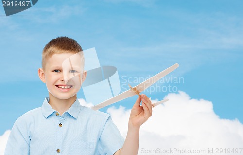 Image of smiling little boy holding a wooden airplane model