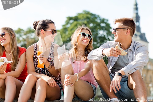 Image of group of smiling friends sitting on city square