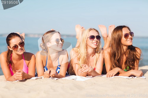 Image of group of smiling women in sunglasses on beach
