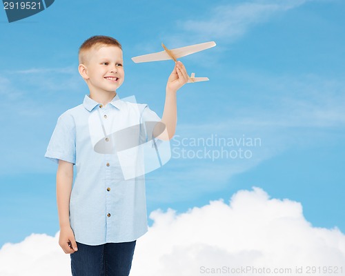 Image of smiling little boy holding a wooden airplane model