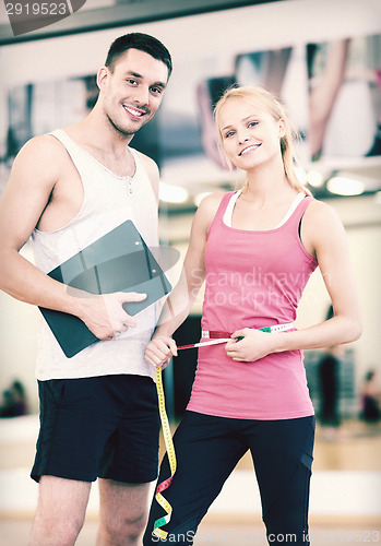 Image of two smiling people with clipboard and measure tape