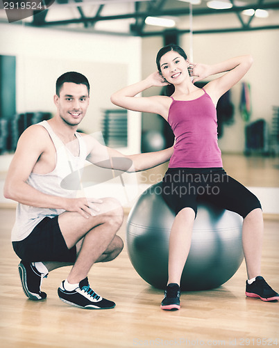 Image of male trainer with woman doing crunches on the ball