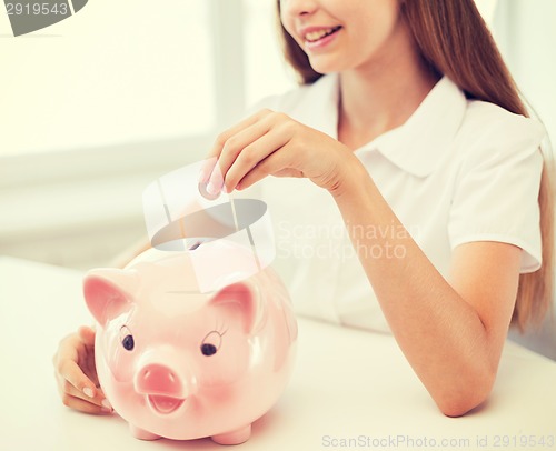 Image of smiling child putting coin into big piggy bank