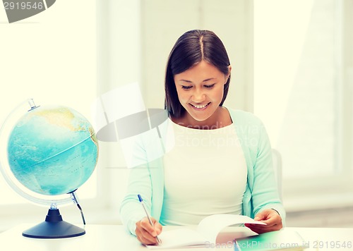 Image of teacher with globe and notepad at school
