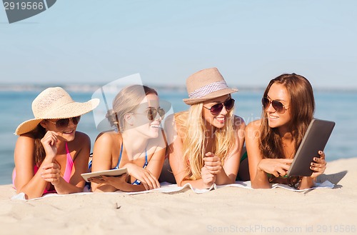 Image of group of smiling young women with tablets on beach