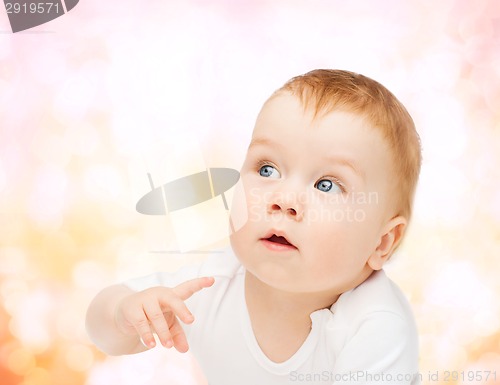 Image of curious baby lying on floor and looking side