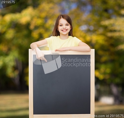 Image of happy little girl pointing finger to blackboard