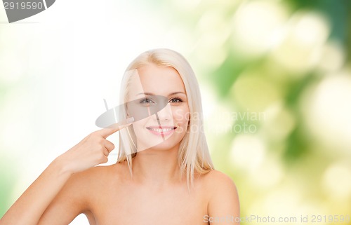 Image of smiling young woman pointing at her cheek