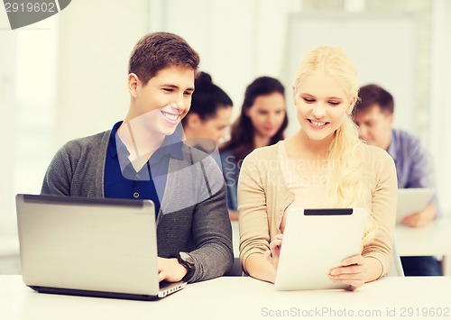 Image of two smiling students with laptop and tablet pc