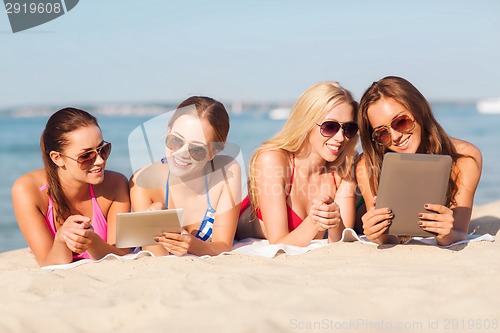 Image of group of smiling young women with tablets on beach