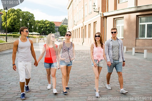 Image of group of smiling friends walking in the city