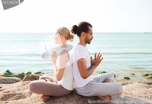 Image of smiling couple making yoga exercises outdoors