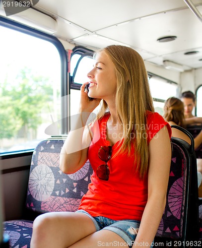 Image of smiling teenage girl with smartphone going by bus