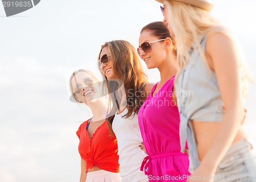 Image of group of smiling women in sunglasses on beach