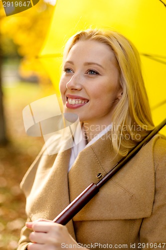 Image of smiling woman with umbrella in autumn park