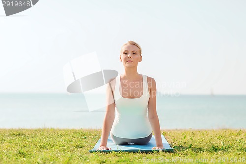 Image of young woman making yoga exercises outdoors