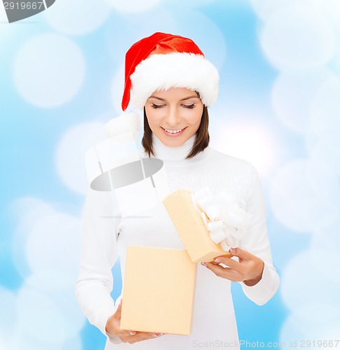 Image of smiling woman in santa helper hat opening gift box