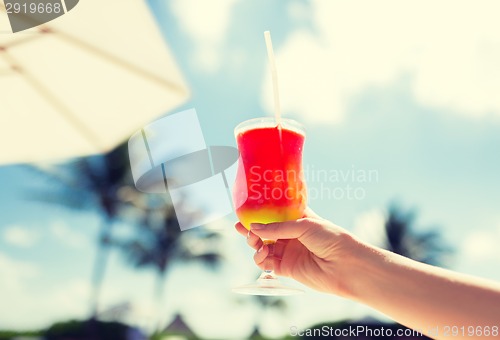 Image of close-up of hand holding glass with cocktail