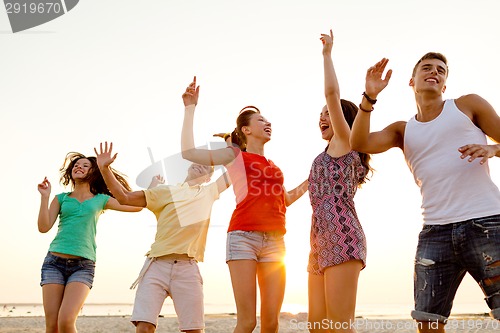 Image of smiling friends dancing on summer beach