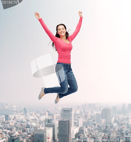 Image of smiling young woman jumping in air