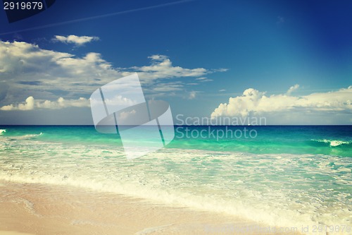 Image of blue sea or ocean, white sand and sky with clouds