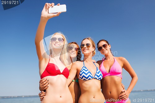 Image of group of smiling women making selfie on beach
