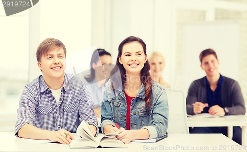 Image of two teenagers with notebooks and book at school