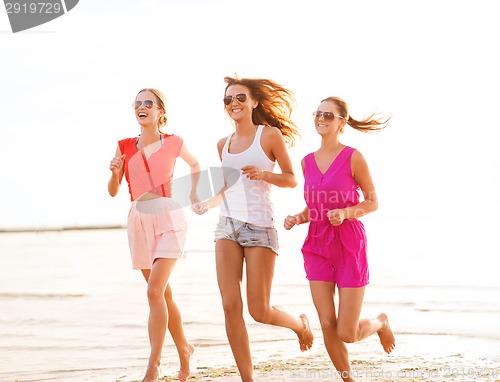 Image of group of smiling women running on beach