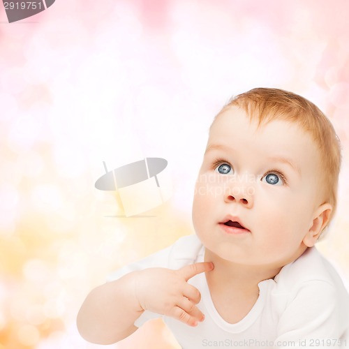 Image of curious baby lying on floor and looking up