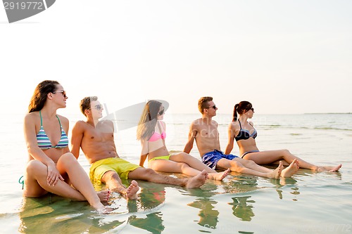 Image of smiling friends in sunglasses on summer beach