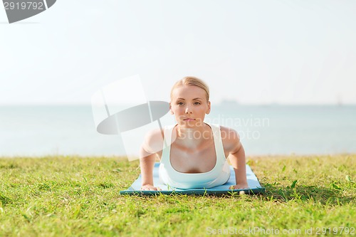 Image of young woman making yoga exercises outdoors
