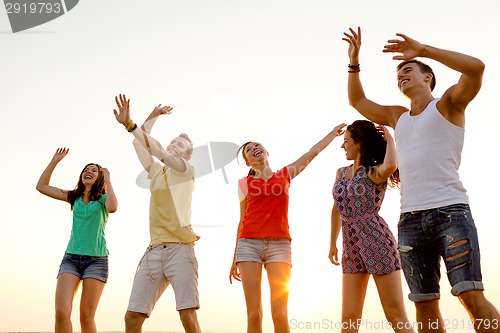 Image of smiling friends dancing on summer beach