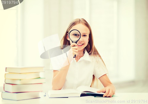 Image of girl reading book with magnifier at school