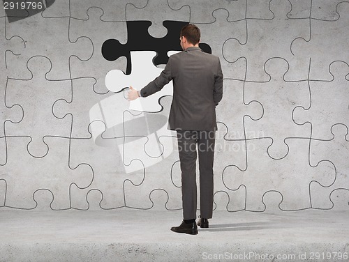 Image of businessman in suit setting piece of puzzle