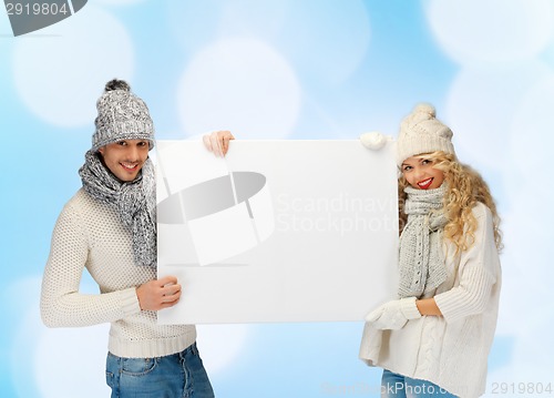 Image of smiling couple in winter clothes with blank board