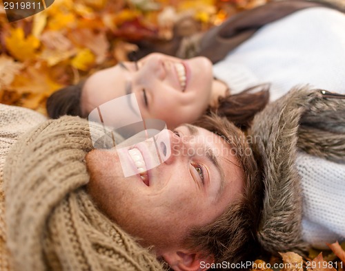 Image of close up of smiling couple lying in autumn park