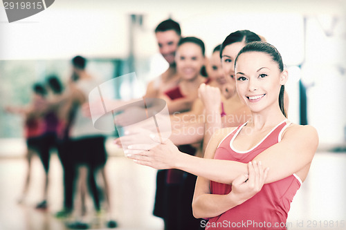 Image of group of smiling people stretching in the gym