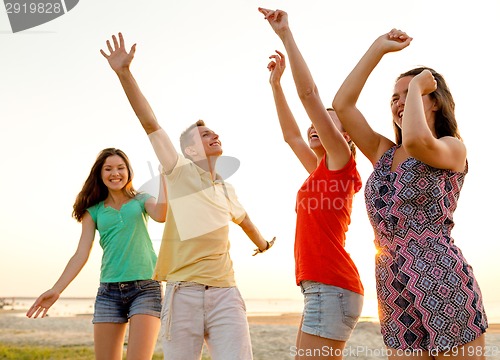 Image of smiling friends dancing on summer beach