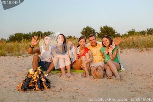 Image of smiling friends in sunglasses on summer beach