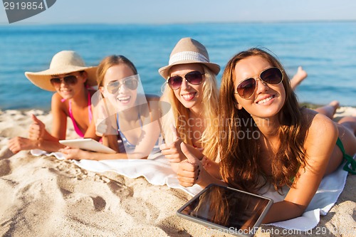 Image of group of smiling young women with tablets on beach