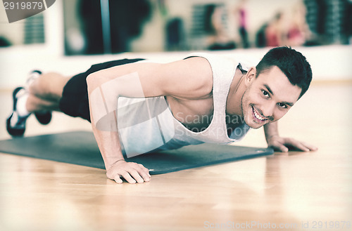 Image of smiling man doing push-ups in the gym