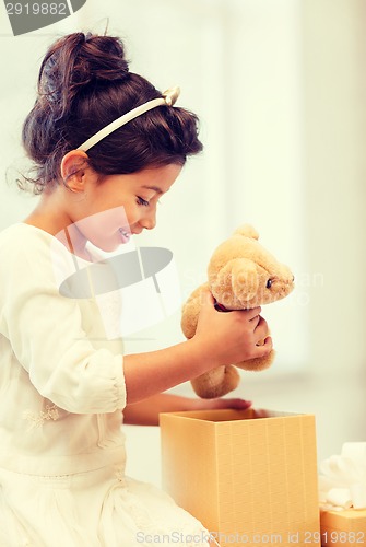 Image of happy child girl with gift box and teddy bear