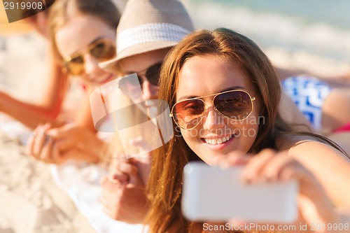 Image of close up of smiling women with smartphone on beach